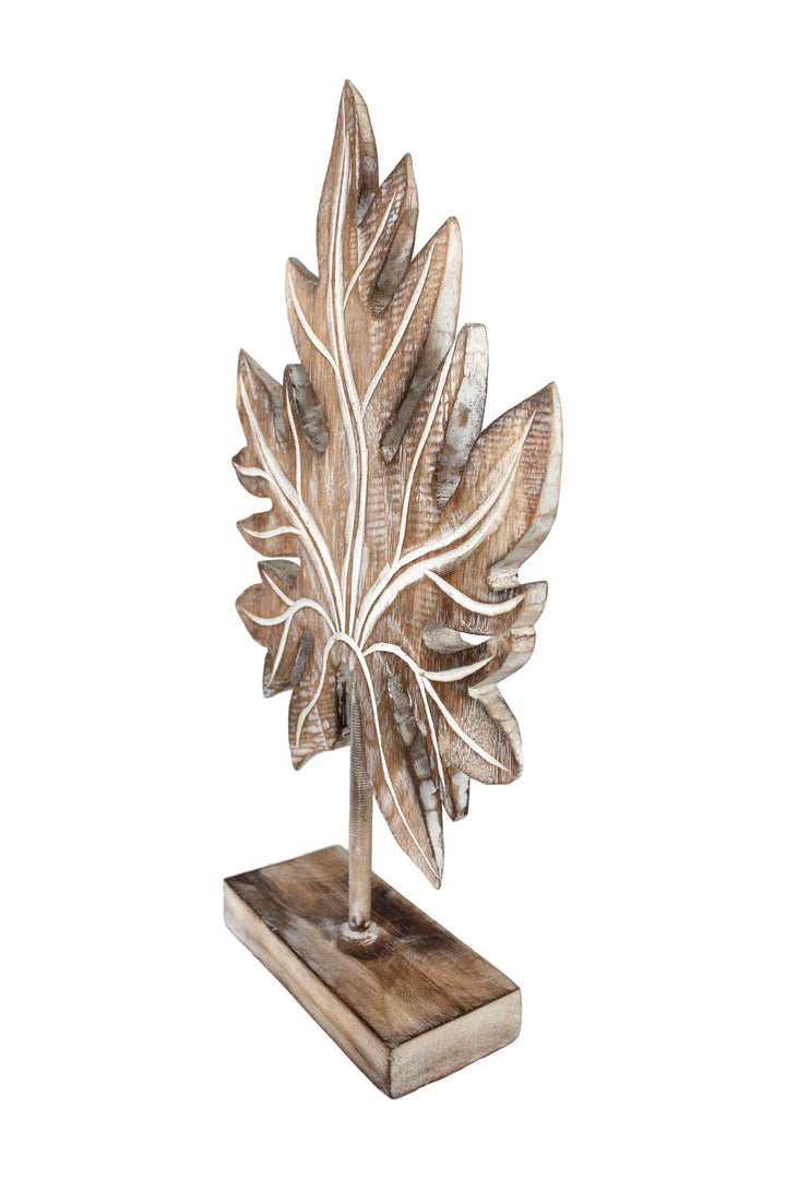 Carved wooden tropical leaf sculpture on a stand.