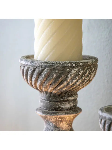 A rustic, grey candlestick holder featuring a distressed finish