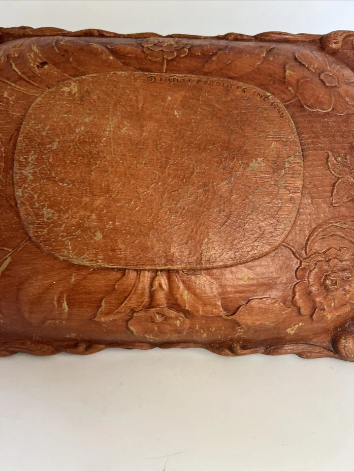 A rectangular brown wooden tray featuring a detailed, high-relief hand-carved floral arrangement of roses and bluebells in the center with a decorative wavy border.