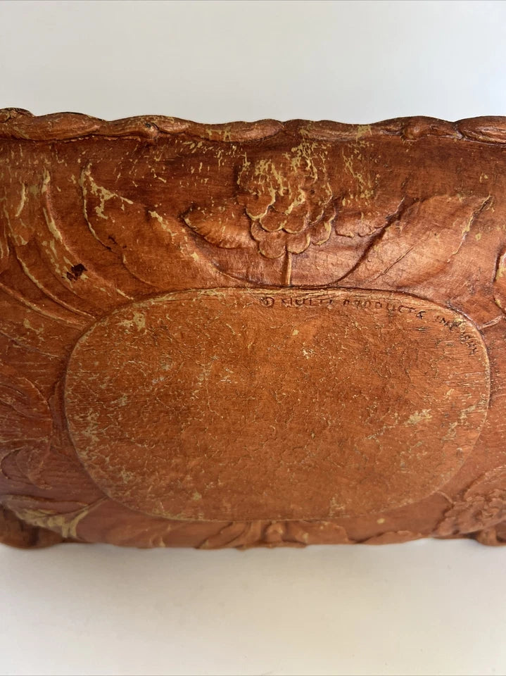 A rectangular brown wooden tray featuring a detailed, high-relief hand-carved floral arrangement of roses and bluebells in the center with a decorative wavy border.