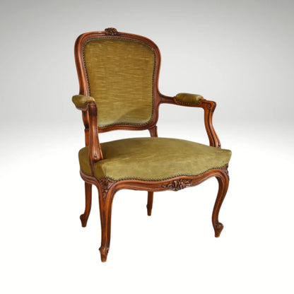 An antique French-style wooden accent chair featuring moss green velvet cushions and curved cabriole legs.