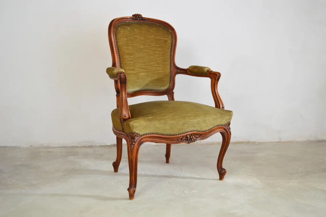 An antique French-style wooden accent chair featuring moss green velvet cushions and curved cabriole legs.