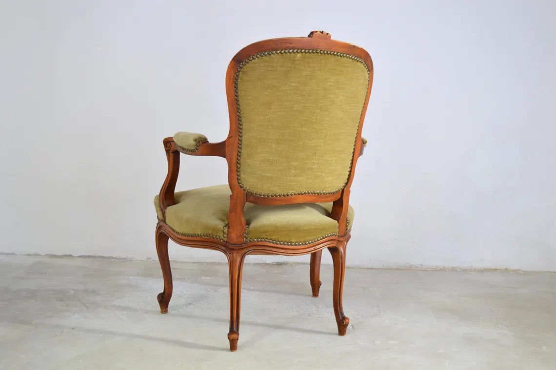 An antique French-style wooden accent chair featuring moss green velvet cushions and curved cabriole legs.