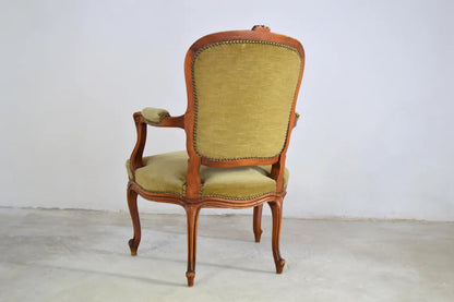 An antique French-style wooden accent chair featuring moss green velvet cushions and curved cabriole legs.