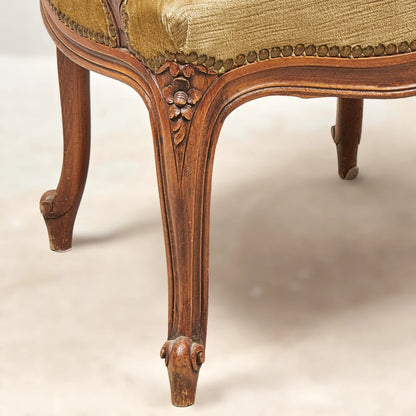 An antique French-style wooden accent chair featuring moss green velvet cushions and curved cabriole legs.