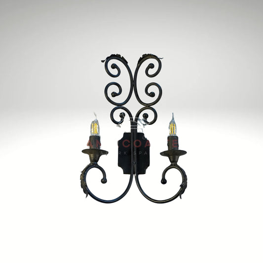 Antique-style black metal double wall lamp featuring elegant scrolls and glowing filament bulbs.