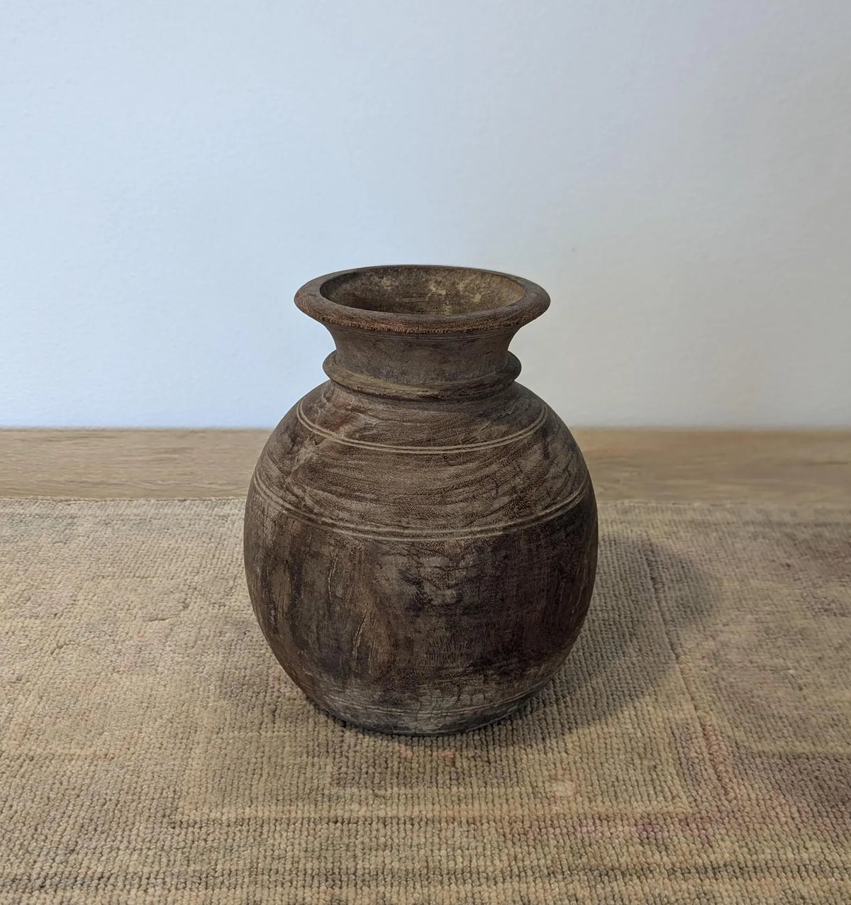 A round, dark brown rustic wooden vase