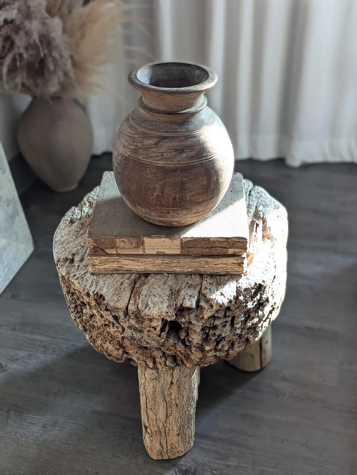 A round, dark brown rustic wooden vase
