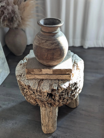 A round, dark brown rustic wooden vase
