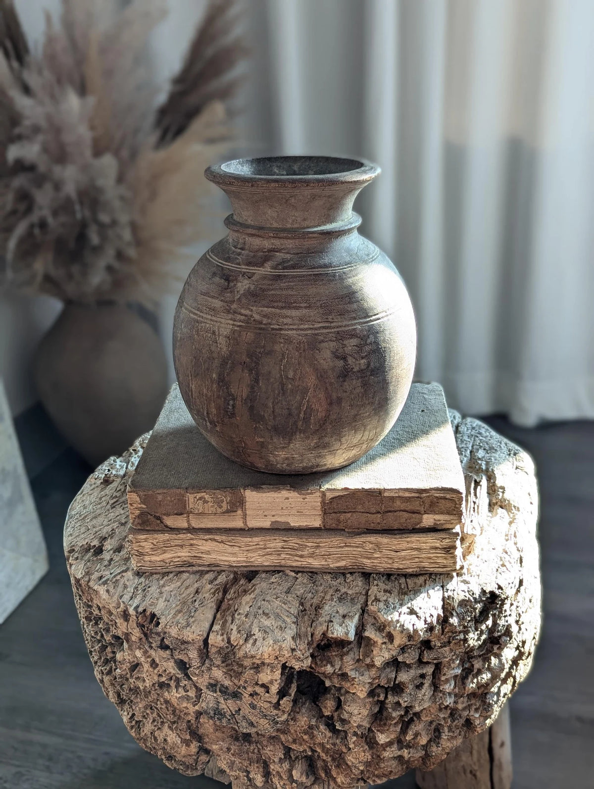 A round, dark brown rustic wooden vase