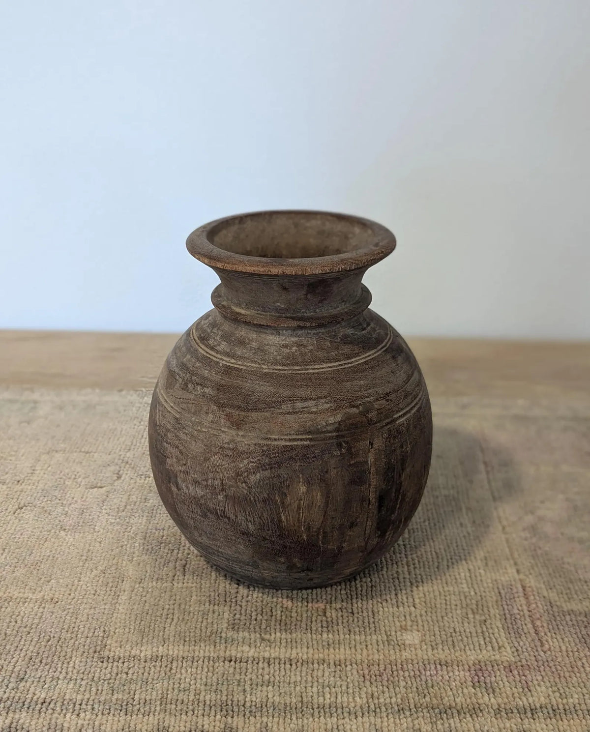 A round, dark brown rustic wooden vase
