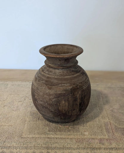 A round, dark brown rustic wooden vase