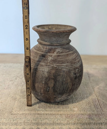 A round, dark brown rustic wooden vase
