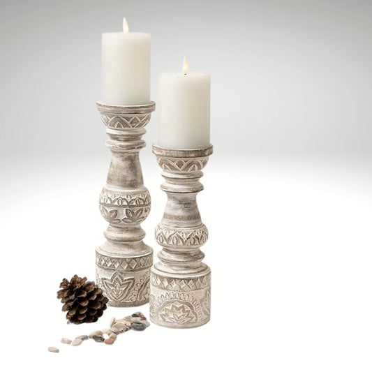 Set of two distressed white boho style pillar candle stands featuring intricate geometric and floral carvings.