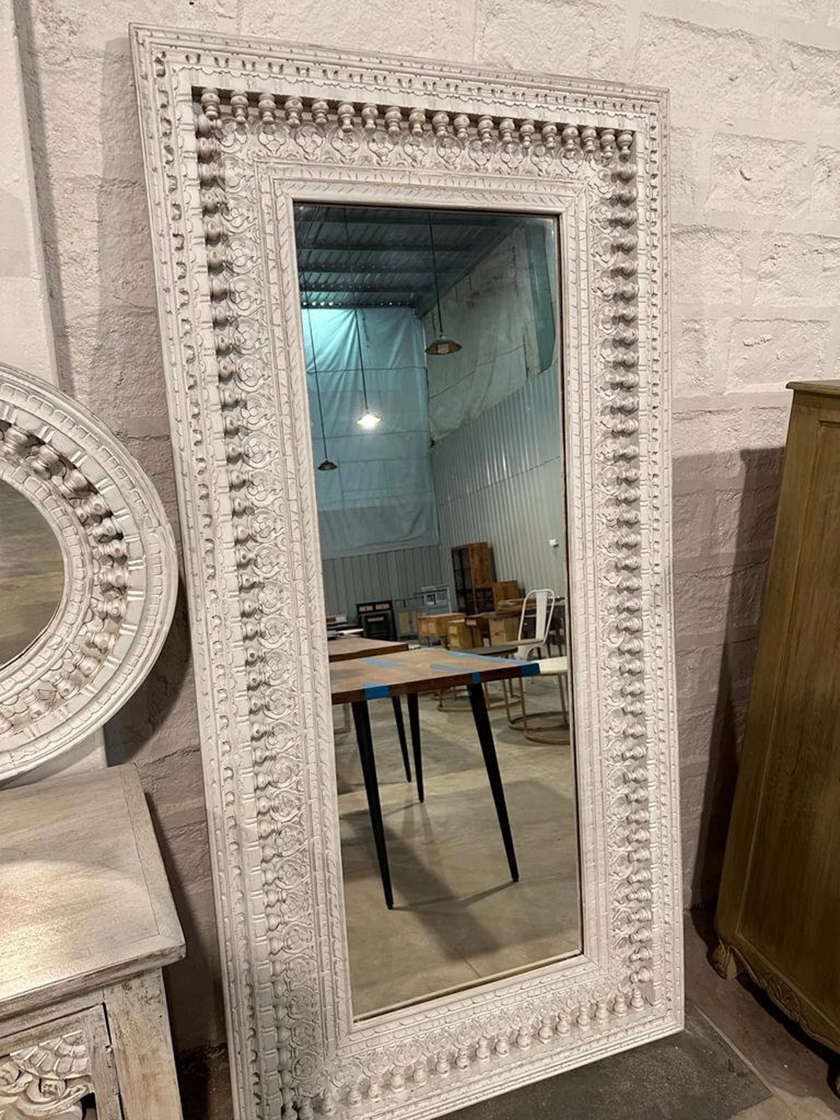 An ornate, rectangular white-washed wooden mirror frame