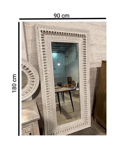 An ornate, rectangular white-washed wooden mirror frame