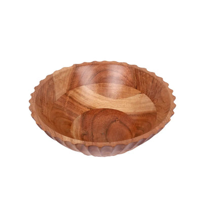 A large, fluted wooden serving bowl with a carved exterior pattern sitting on a concrete countertop.