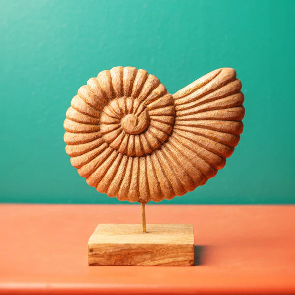 A decorative carved wooden nautilus shell sculpture mounted on a metal rod with a square wooden base.
