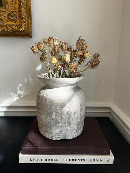 A rustic, light-colored wooden vase with a textured, ribbed surface and a natural wood rim sitting on a dark surface.
