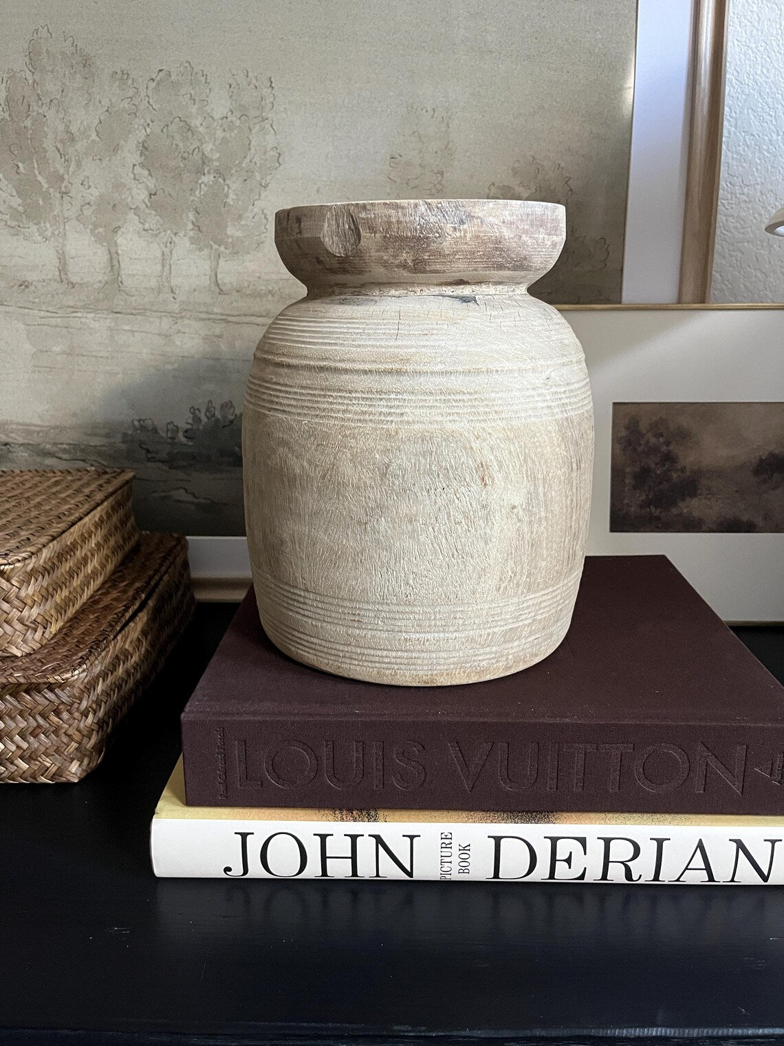 A rustic, light-colored wooden vase with a textured, ribbed surface and a natural wood rim sitting on a dark surface.