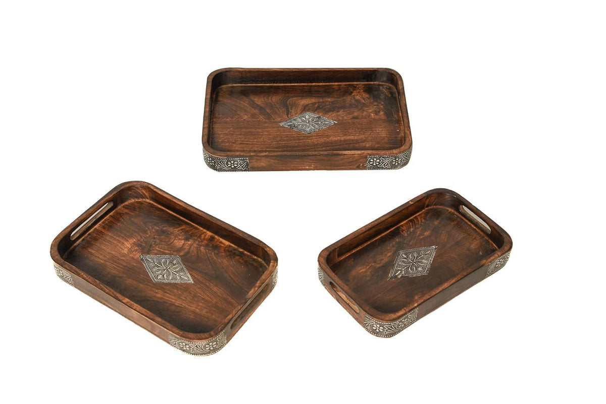 A stack of three rectangular dark brown wooden serving trays featuring ornate metal diamond inlays in the center and decorative metal borders along the corners.