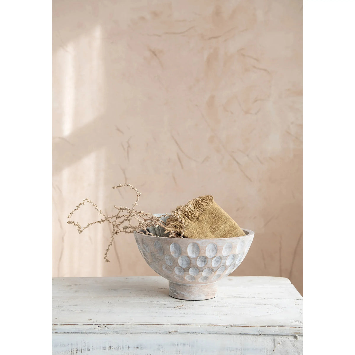A round, natural mango wood bowl with a footed base and a carved, circular pattern decorating the outer surface.