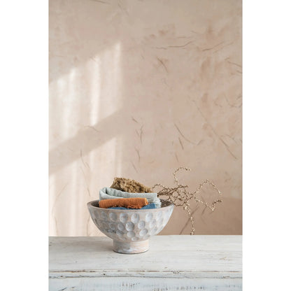 A round, natural mango wood bowl with a footed base and a carved, circular pattern decorating the outer surface.