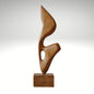 An abstract biomorphic wood sculpture with smooth curves and a hollow cutout, mounted on a square wooden base.