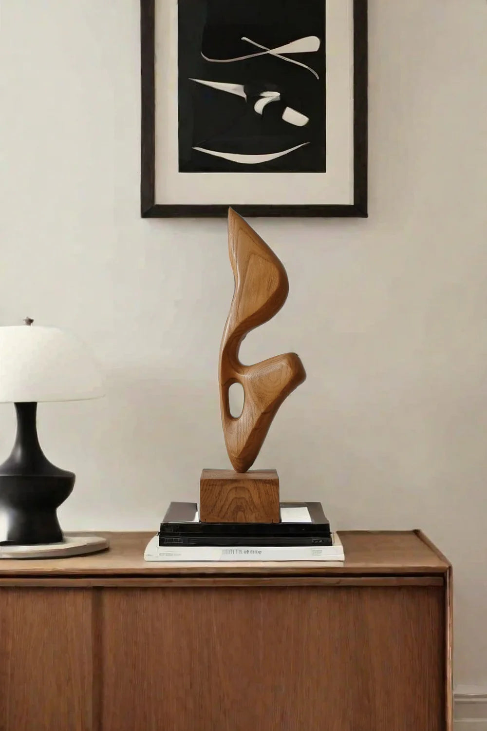 An abstract biomorphic wood sculpture with smooth curves and a hollow cutout, mounted on a square wooden base.