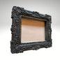  An ornate, dark brown antique-style photo frame with intricate floral carvings 