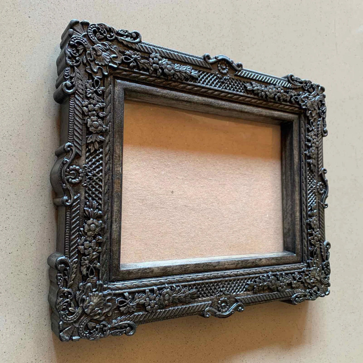  An ornate, dark brown antique-style photo frame with intricate floral carvings 