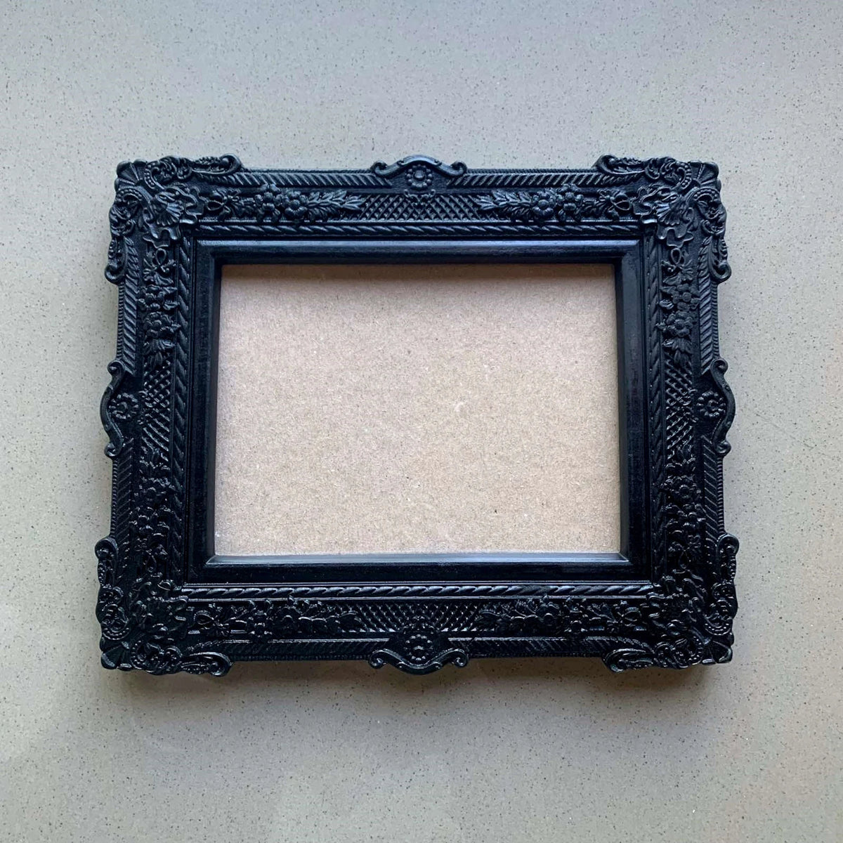  An ornate, dark brown antique-style photo frame with intricate floral carvings 