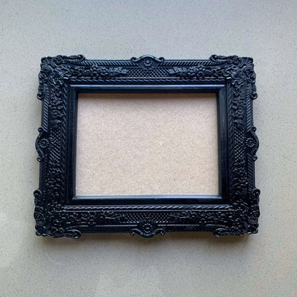  An ornate, dark brown antique-style photo frame with intricate floral carvings 