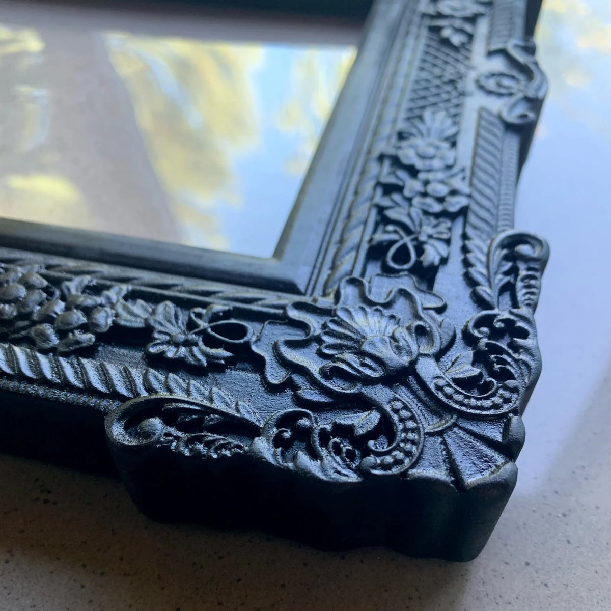  An ornate, dark brown antique-style photo frame with intricate floral carvings 
