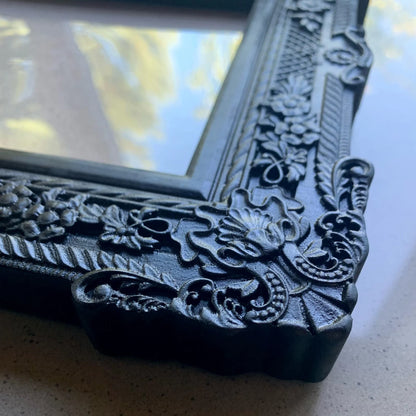  An ornate, dark brown antique-style photo frame with intricate floral carvings 