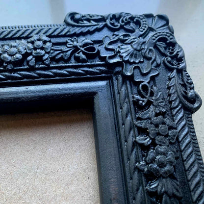  An ornate, dark brown antique-style photo frame with intricate floral carvings 
