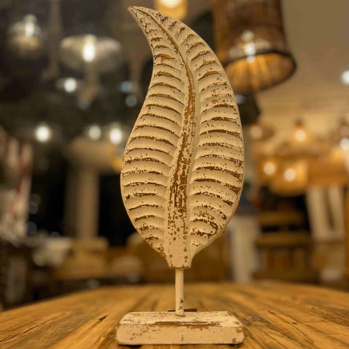  Distressed white metal leaf statue with rustic brown accents mounted on a stand.