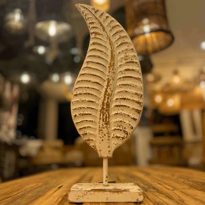  Distressed white metal leaf statue with rustic brown accents mounted on a stand.