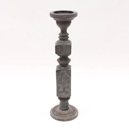 A pair of tall, hand-carved wooden pillar candle holders with a distressed black finish
