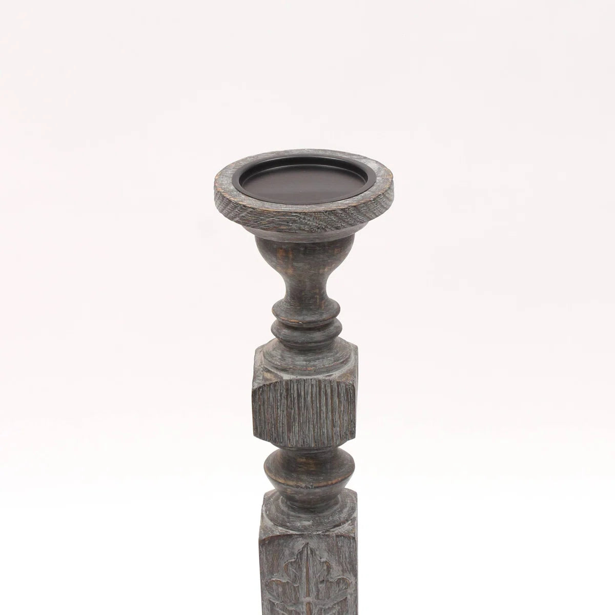 A pair of tall, hand-carved wooden pillar candle holders with a distressed black finish