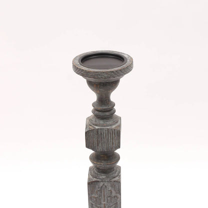 A pair of tall, hand-carved wooden pillar candle holders with a distressed black finish
