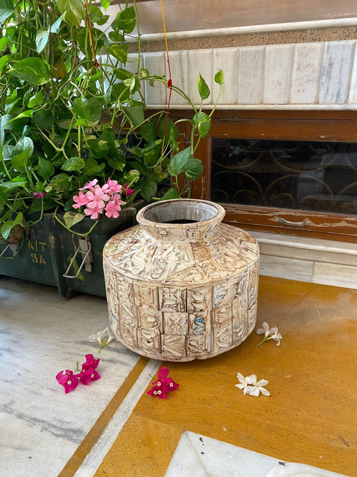 A short, wide ceramic vase featuring textured, block-stamped relief patterns in off-white and beige earthy tones.