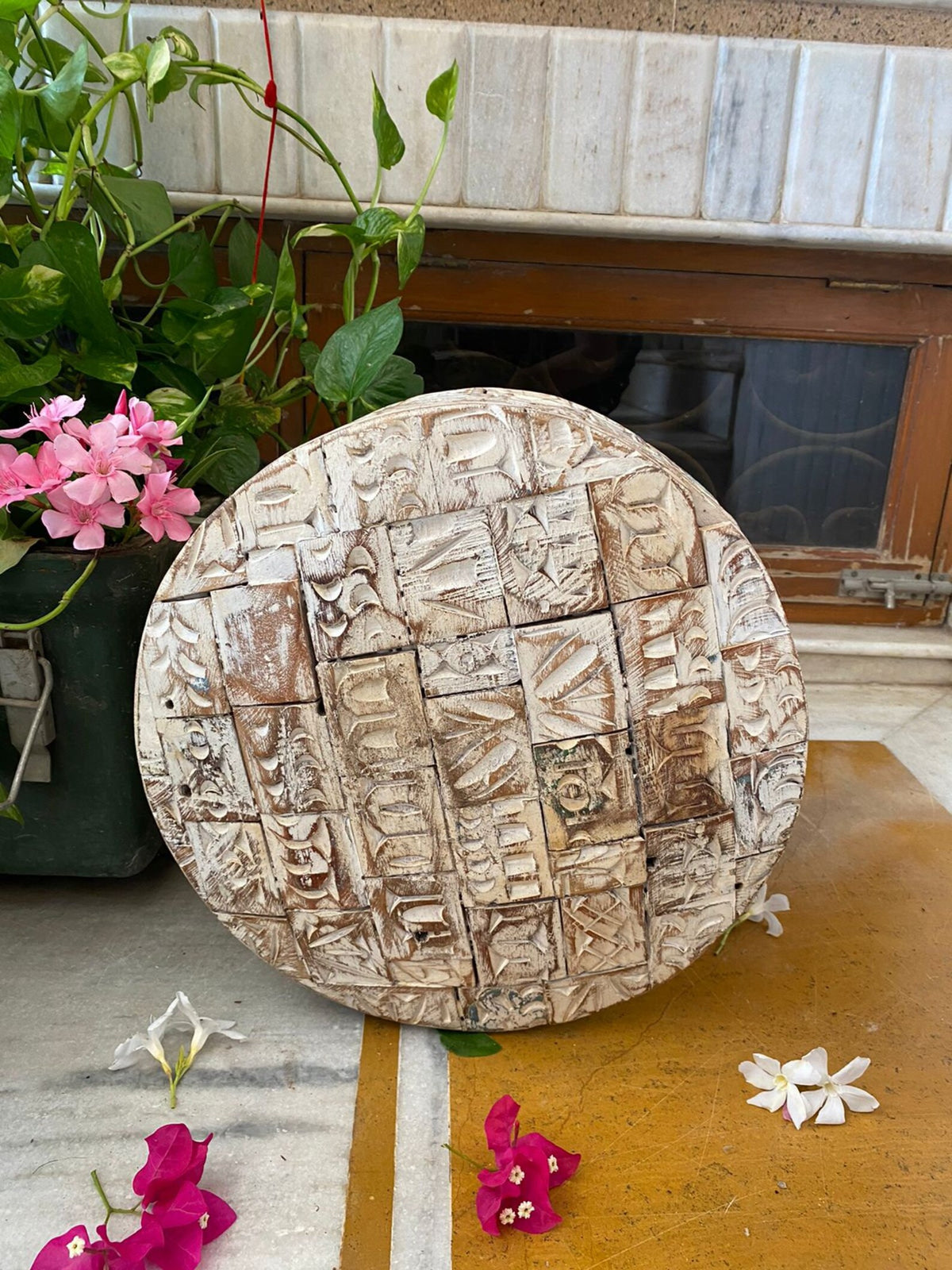 A short, wide ceramic vase featuring textured, block-stamped relief patterns in off-white and beige earthy tones.