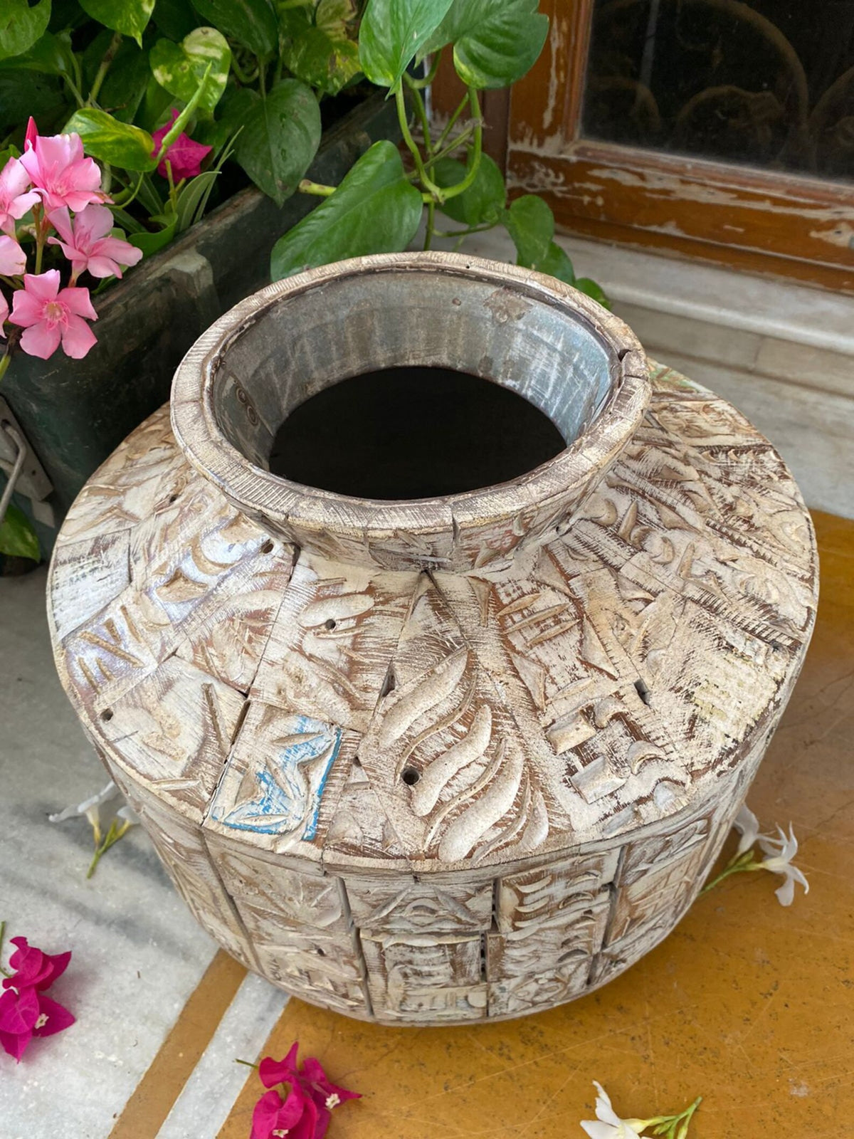 A short, wide ceramic vase featuring textured, block-stamped relief patterns in off-white and beige earthy tones.