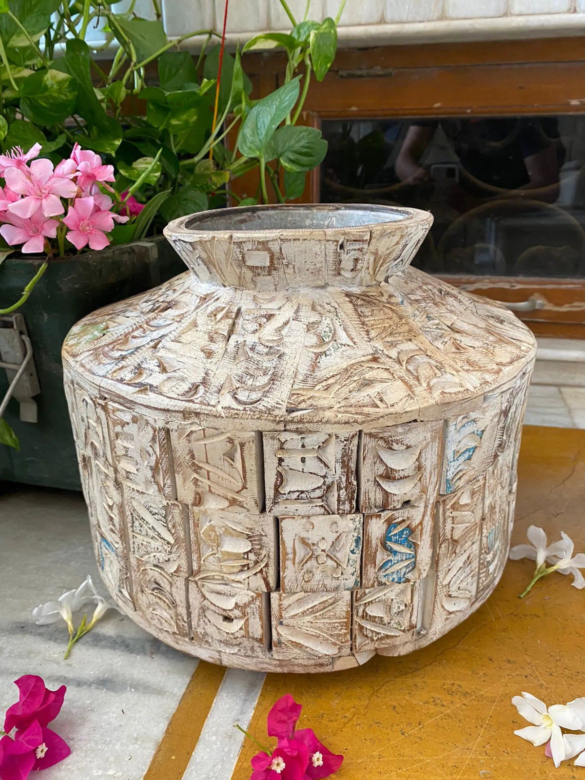 A short, wide ceramic vase featuring textured, block-stamped relief patterns in off-white and beige earthy tones.