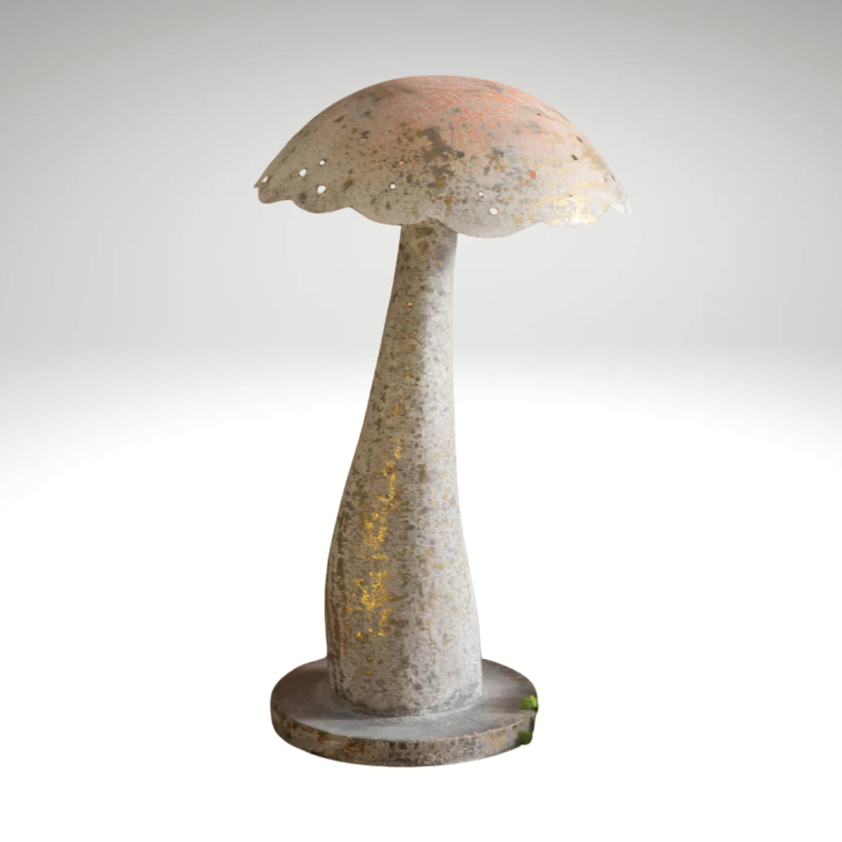 A rustic, mushroom-shaped decorative piece with a textured light-colored finish and golden highlights, placed on a wooden table alongside potted