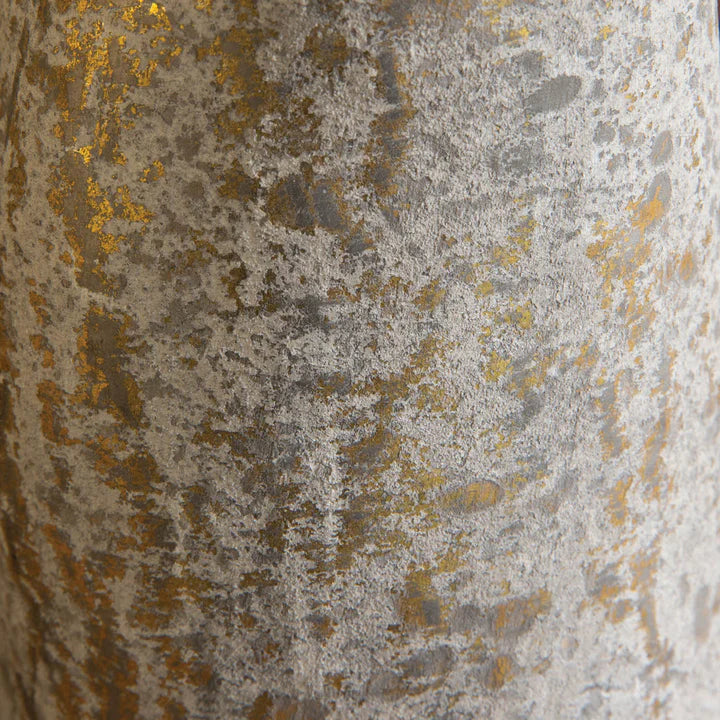 A rustic, mushroom-shaped decorative piece with a textured light-colored finish and golden highlights, placed on a wooden table alongside potted.