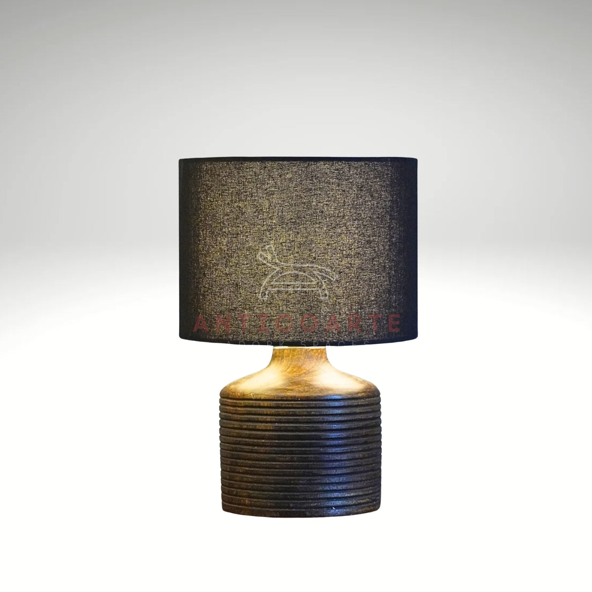 A modern table lamp featuring a dark, ribbed cylindrical wooden base paired with a sleek black drum fabric shade.