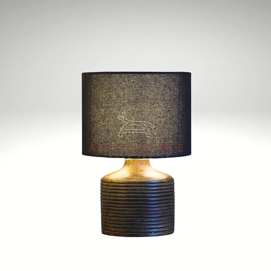 A modern table lamp featuring a dark, ribbed cylindrical wooden base paired with a sleek black drum fabric shade.