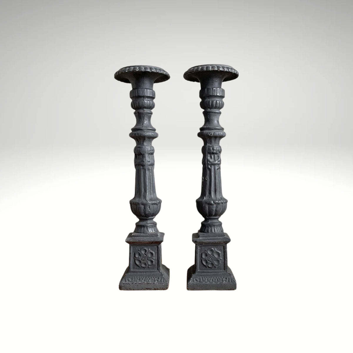 A pair of vintage, ornate dark grey wooden candle holders.